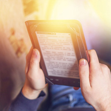 Un homme lit un livre sur sa tablette numérique